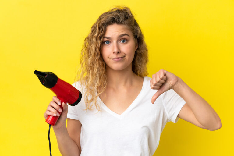 jeune femme blonde tenant un sèche cheveux